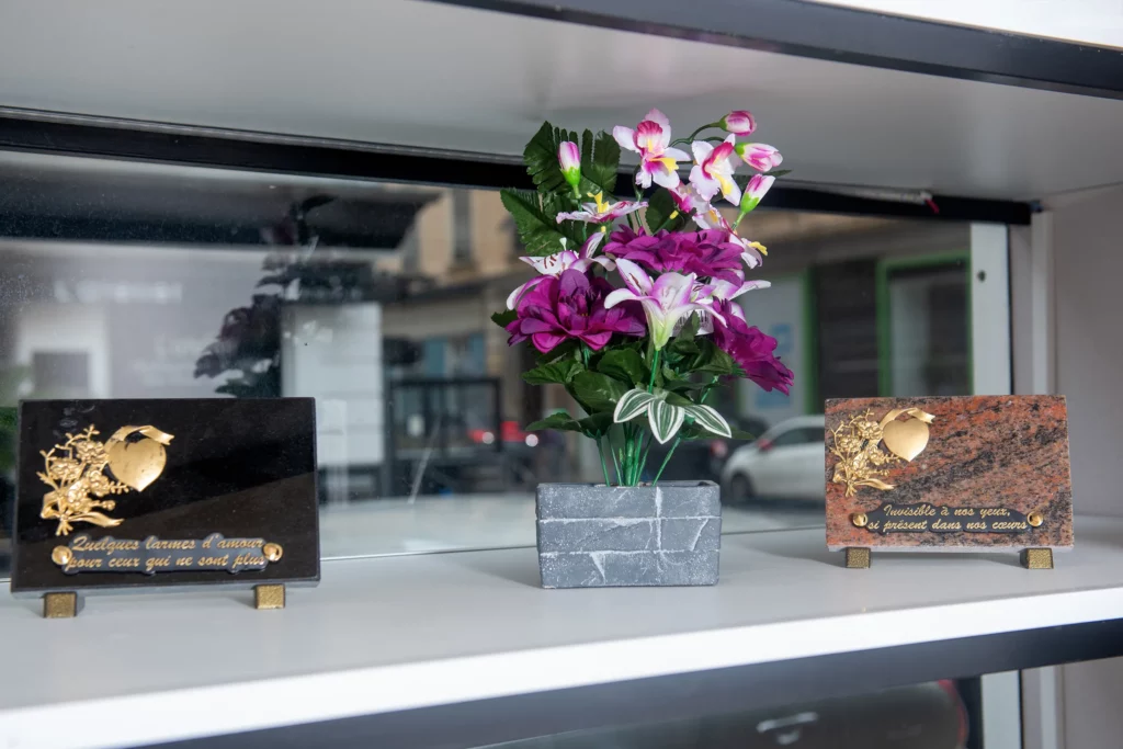 Plaques funéraires personnalisées et arrangement de fleurs artificielles en vitrine